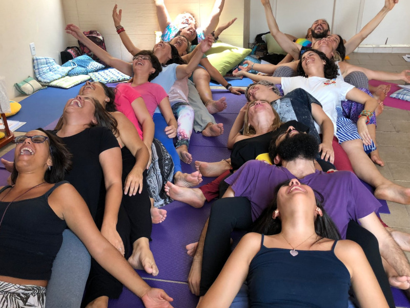 Imagem de participantes numa sesso de yoga do riso, deitados no cho com os braos abertos e expresses de gargalhada