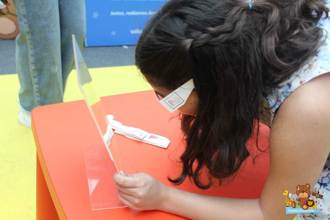 Criança tenta ler com os óculos, identificados com o logo da Íris Inclusiva