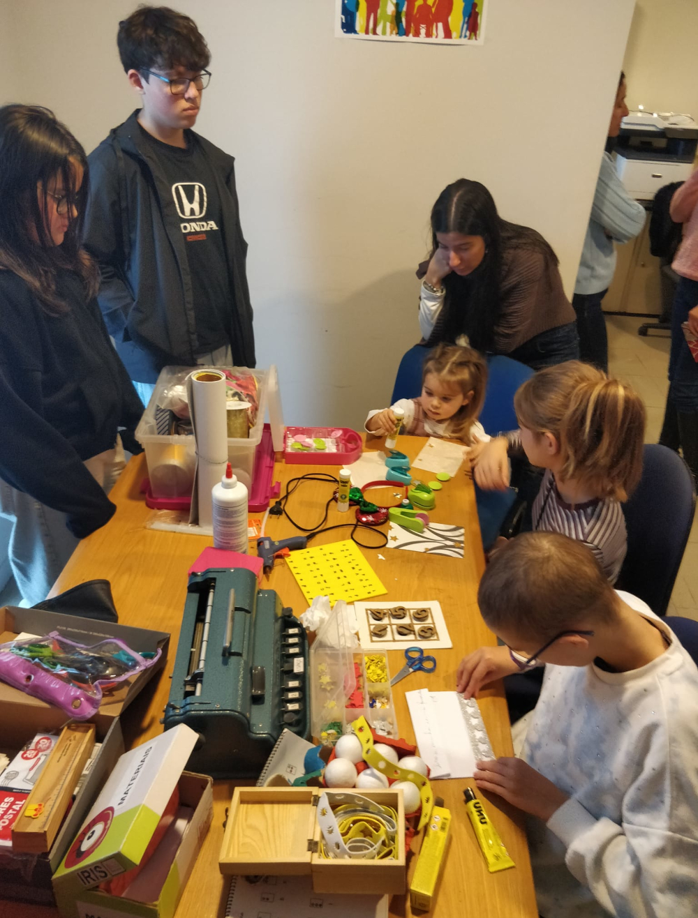 Mesa dedicada à produção de postais de Natal em Braille, com vários participantes na Festa